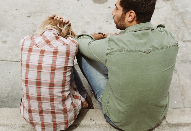 A Couple Sitting On Pavement