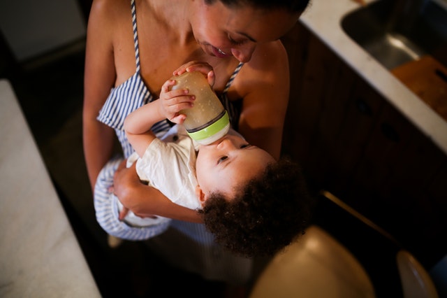 Woman in Black and White Stripe Tank Top Carrying Baby