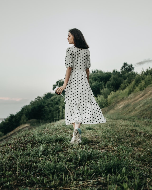  Woman in polka dot white dress walking in countryside 