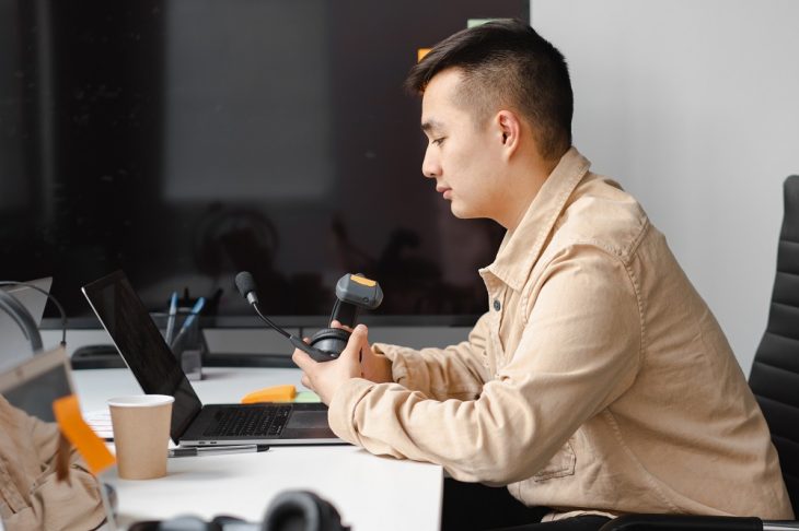 Man sitting in front of a laptop while holding a headset