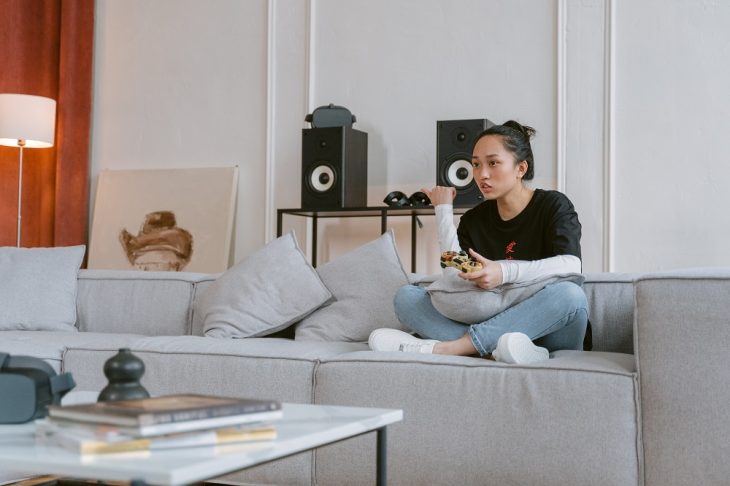 Woman Playing Video Games whileSitting on Gray Sofa