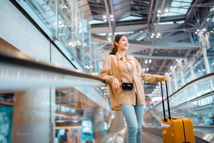 young asian woman at an airport with her suitcase