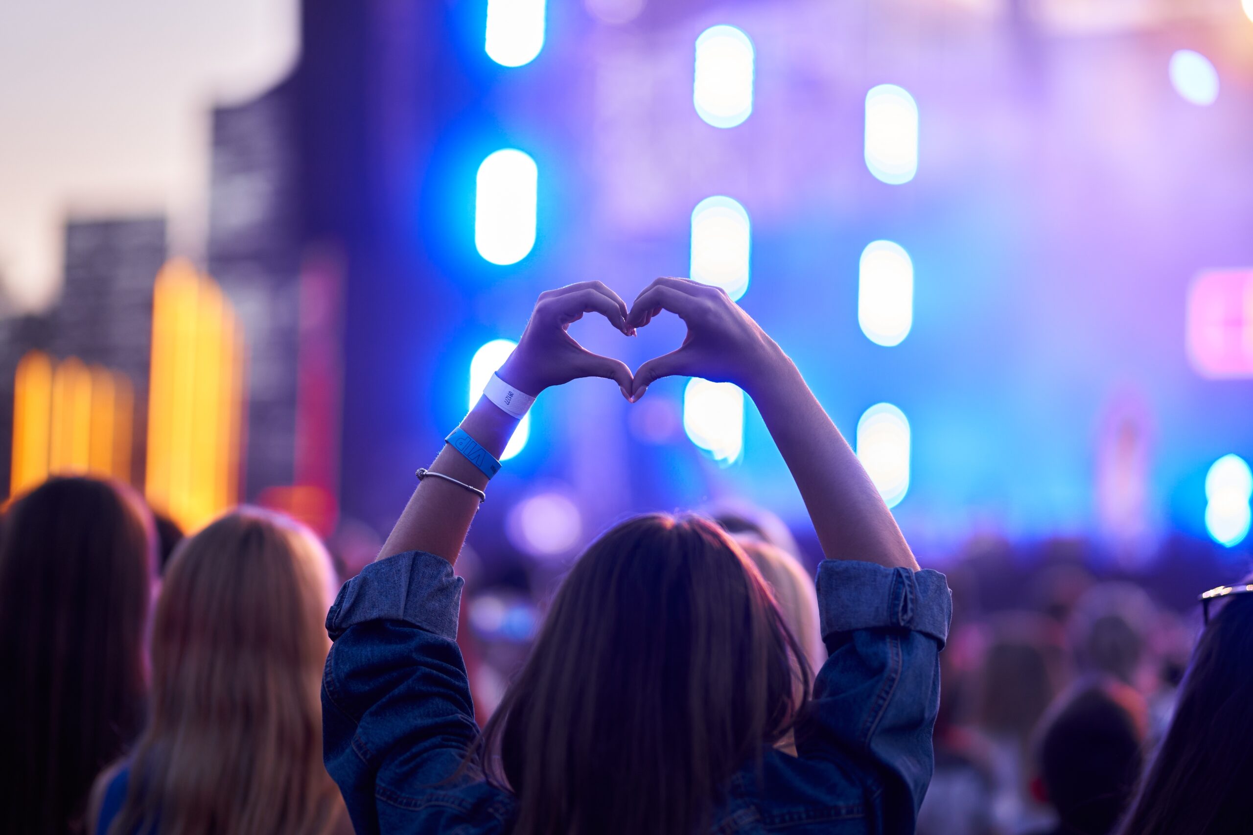 a woman doing a heart shape at a concert