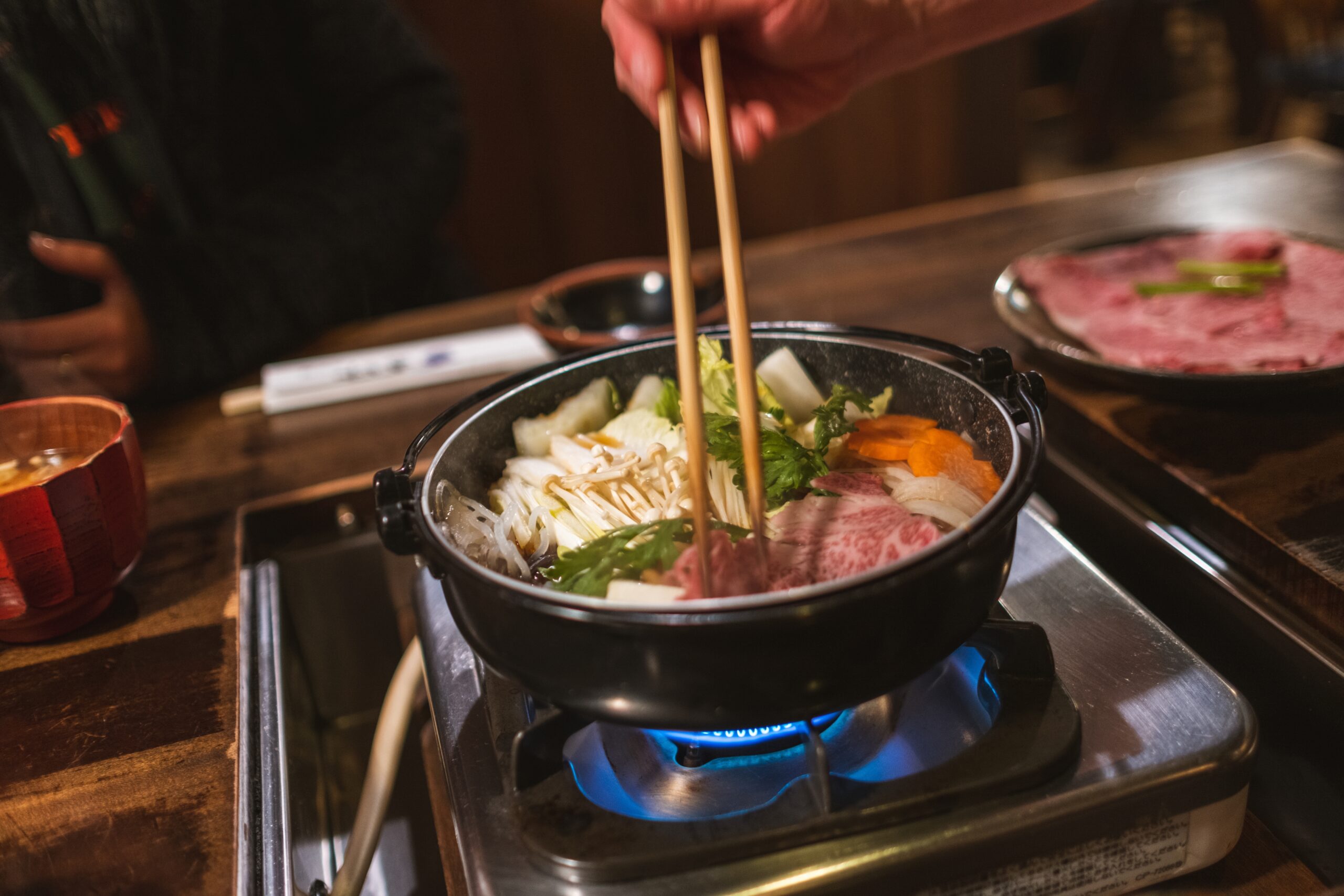 a hotpot set up with a person stirring the soup