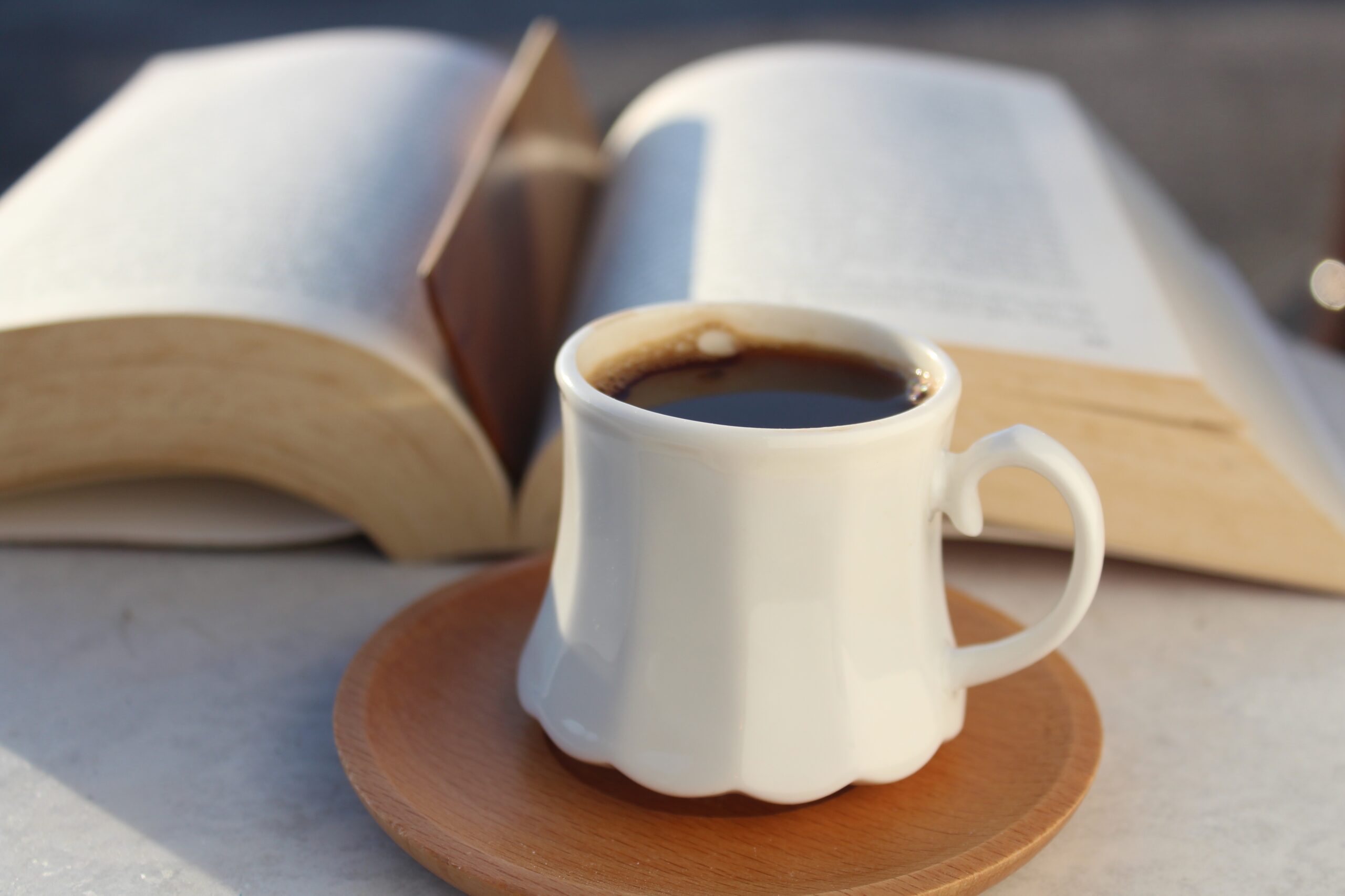 coffee on a ceramic mug beside a book
