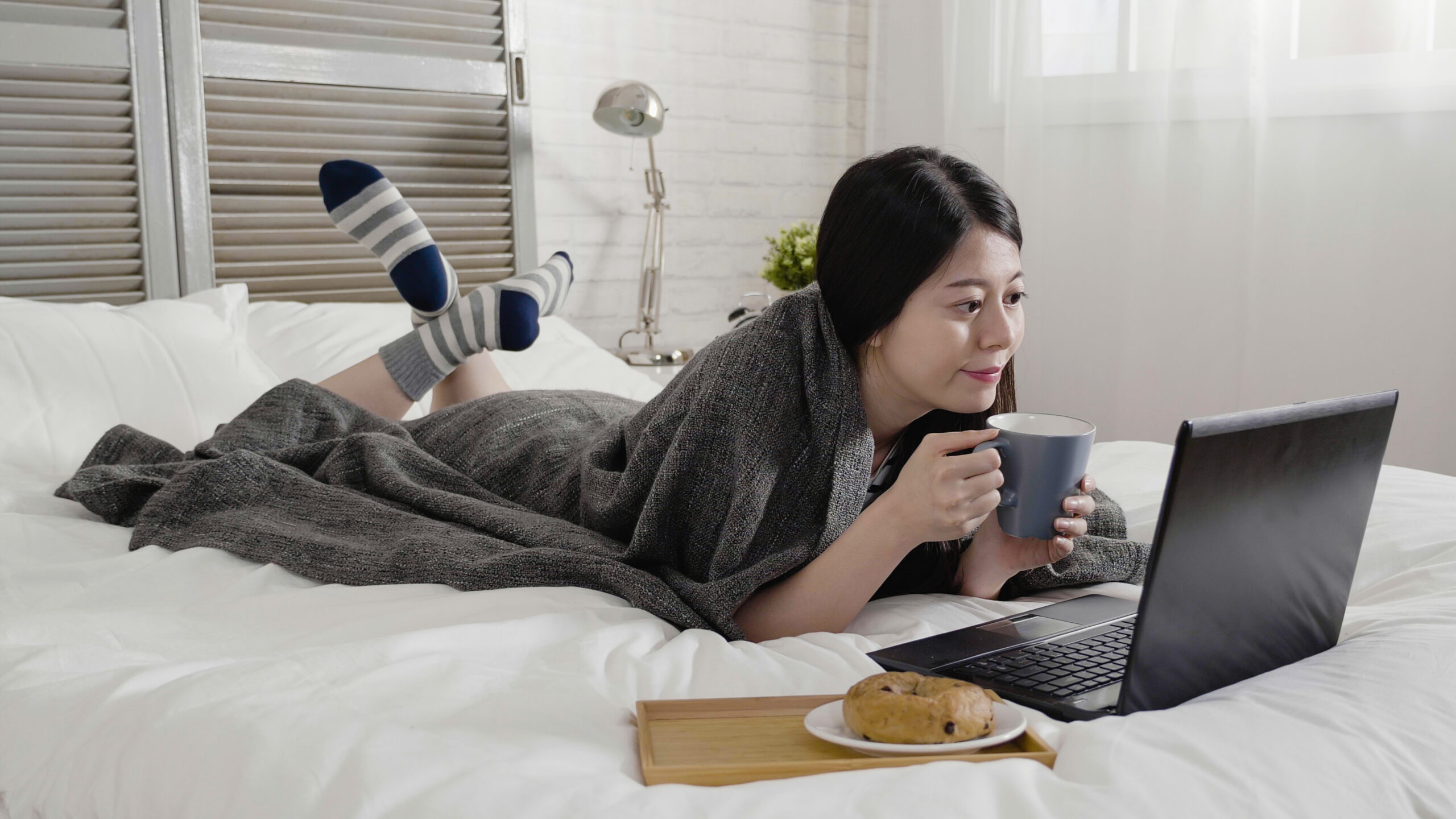 a woman watching a film on her bed