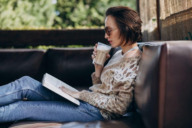 woman reading a book while drinking coffee.