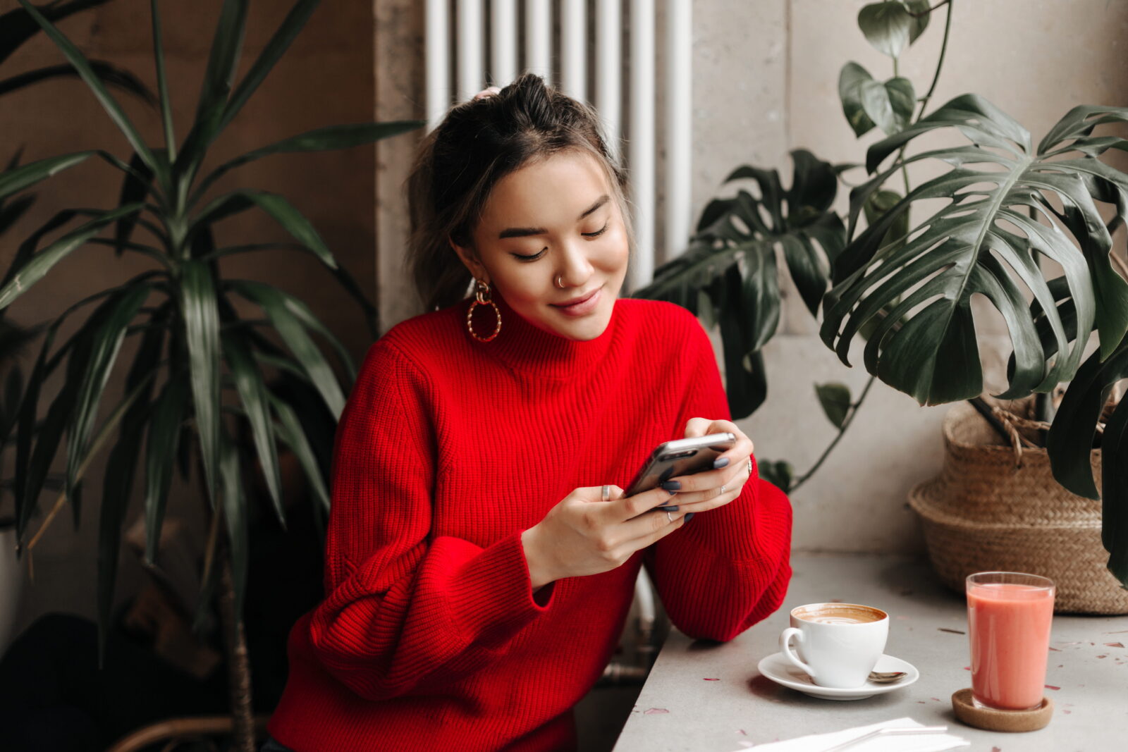 young woman chats on phone while sitting in cafe over cup of coffee