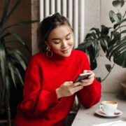 young woman chats on phone while sitting in cafe over cup of coffee