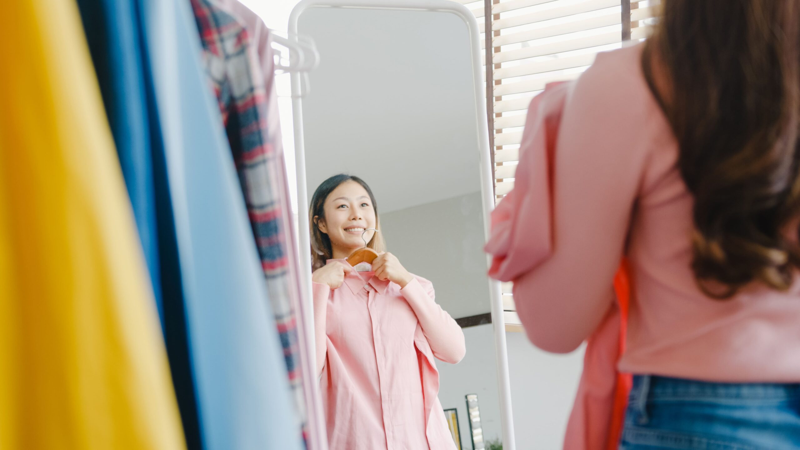 Woman smiling while applying face cream in front of a mirror