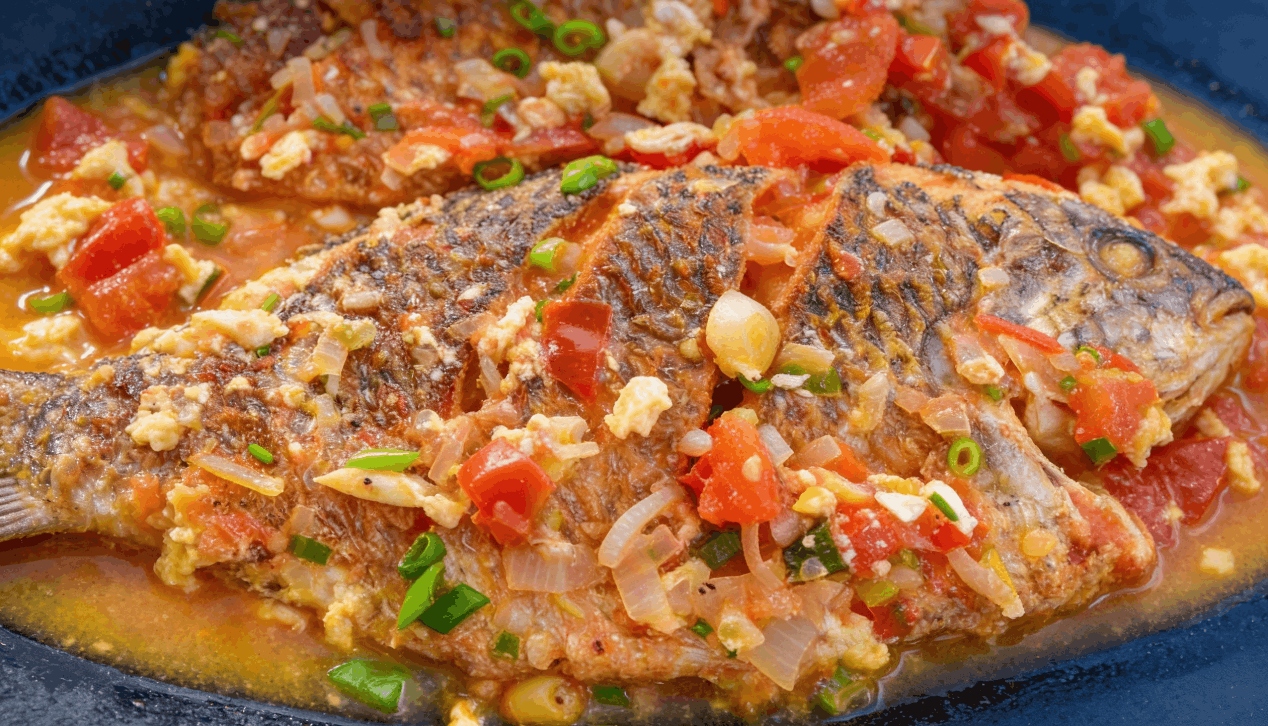 Fried fish steaks simmered in a rich tomato-based sauce with sliced bell peppers, onions, and garlic.