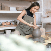 A woman shaping clay on a pottery wheel in a studio