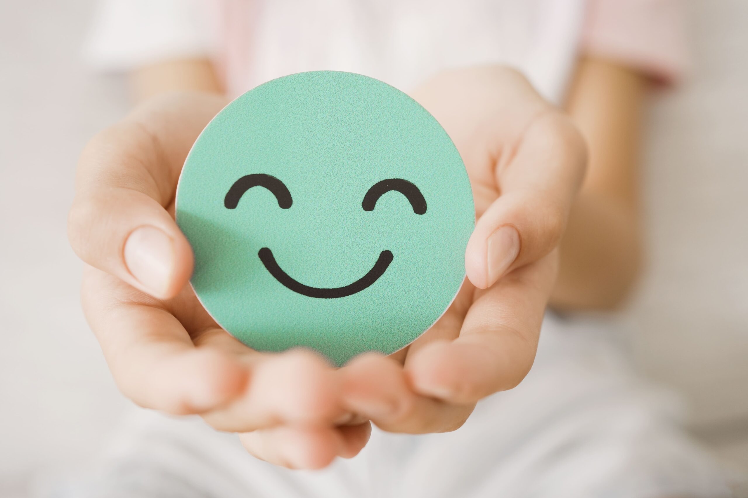 Hands holding green happy smile face paper cut
