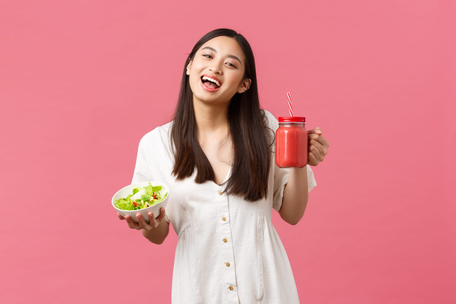 Smiling woman holding salad and smoothie