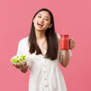 Smiling woman holding salad and smoothie