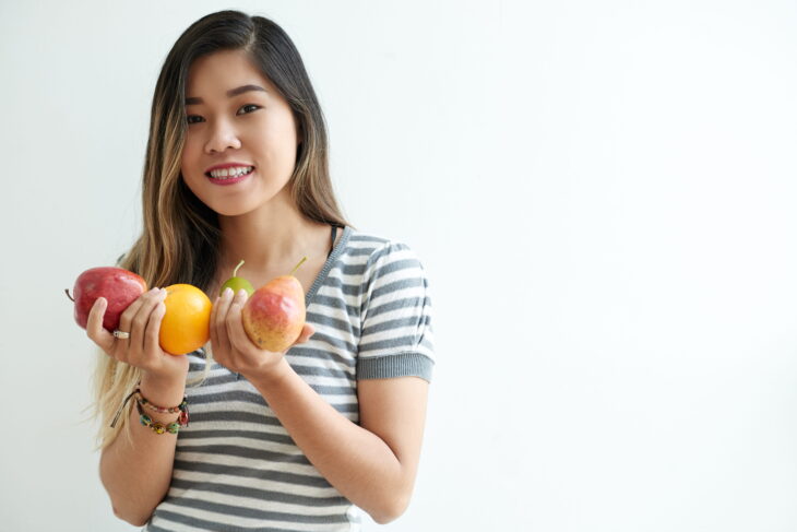 Woman holding fresh fruits, promoting healthy eating and balanced nutrition