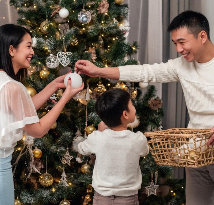 A family smiling together while hanging ornaments on a decorated Christmas tree.
